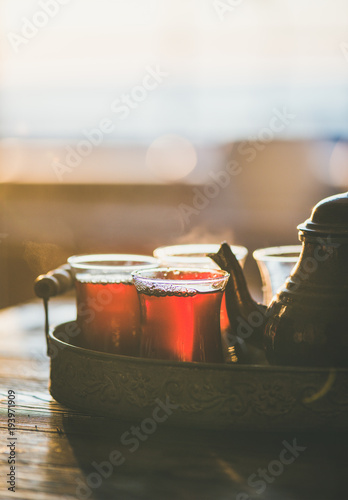 Freshly brewed traditional black tea in turkish tukip glasses and teapot in oriental tray, selective focus, copy space, vertical composition