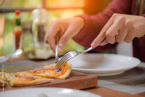 Woman hands using spoon and fork taking slices of pizza