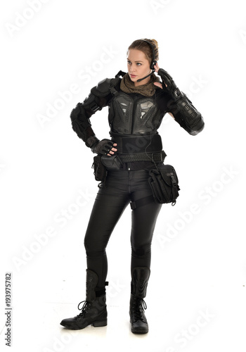full length portrait of female soldier wearing black tactical armour, isolated on white studio background.