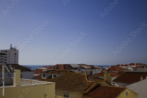 the roofs of a small Portuguese town with the ocean in the background