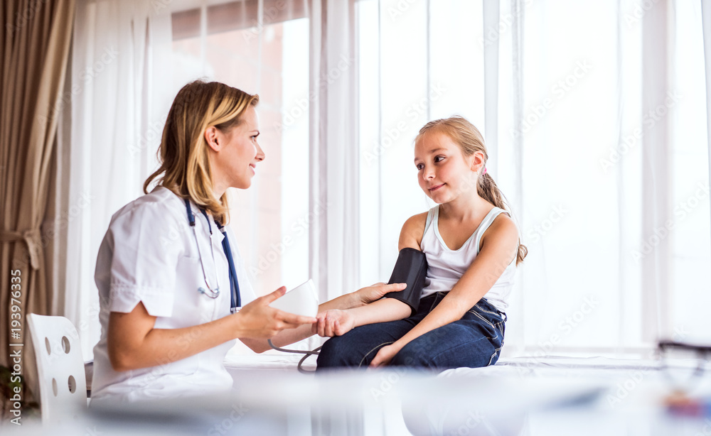 Obraz premium Young female doctor checking a small girl in her office.