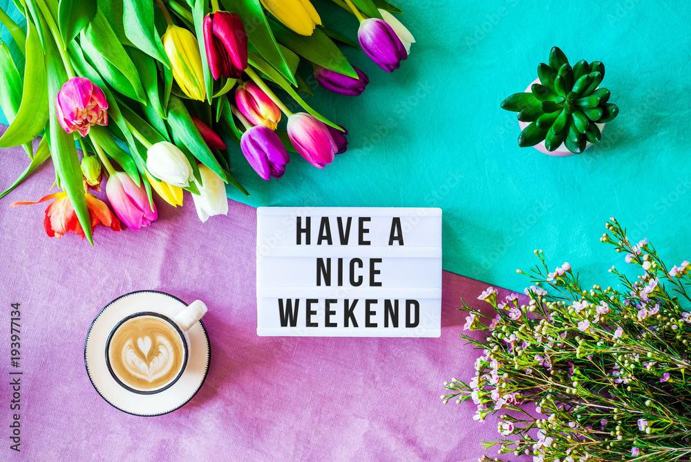 Fototapeta Życzymy miłego weekendu zapisanego w lightboxie z wiosennymi kwiatami z góry