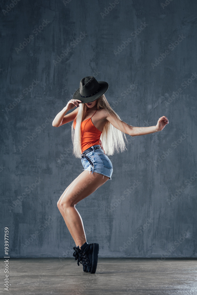 Young beautiful female dancer is posing in the studio