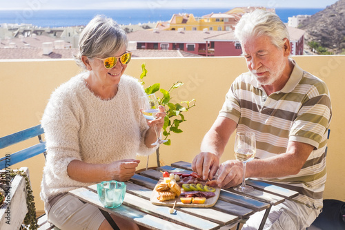 senior couple haveing a breakfast with food and drink on the rooftop outdoor with ocean view