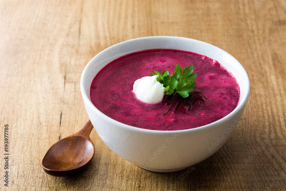 Beet soup in white bowl on wooden table Beet soup in white bowl on wooden table