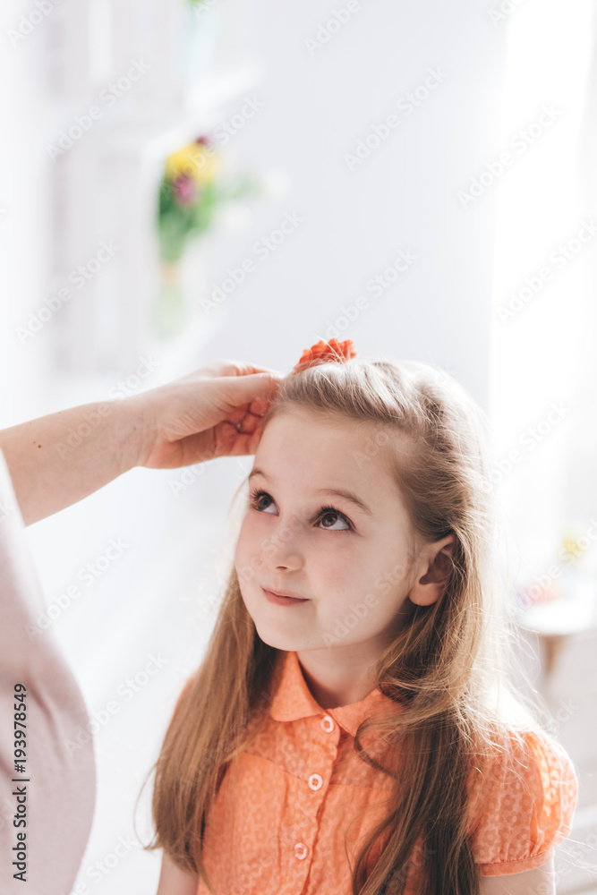 Naklejka premium Mother fixing her young daughter's hair