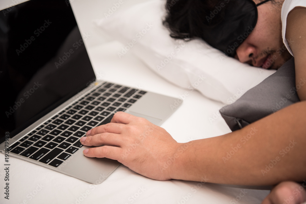 Naklejka premium Asian man is sleeping on the bed in bedroom leave his work on computer.