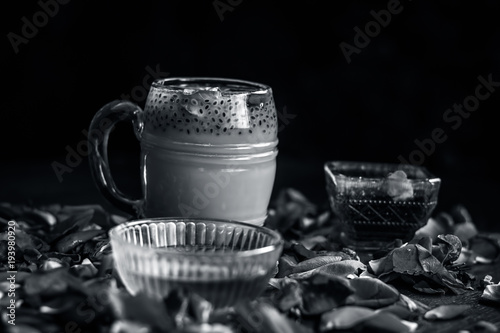 Indian/Asian popular summer drink i.e. Gulab Shake or Rose shake consisting of milk,rose syrup,sugar and honey with sabja seeds or sweet basil seeds in a transparent glass,with all ingredients.