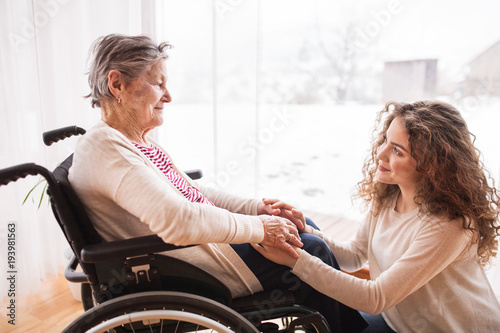 A teenage girl with grandmother at home, holding hands.