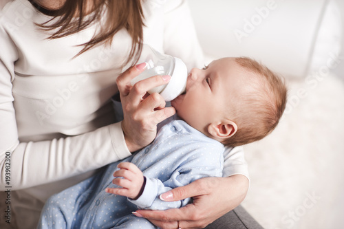 Принти на полотні Baby boy drinking milk from bottle holding by mother