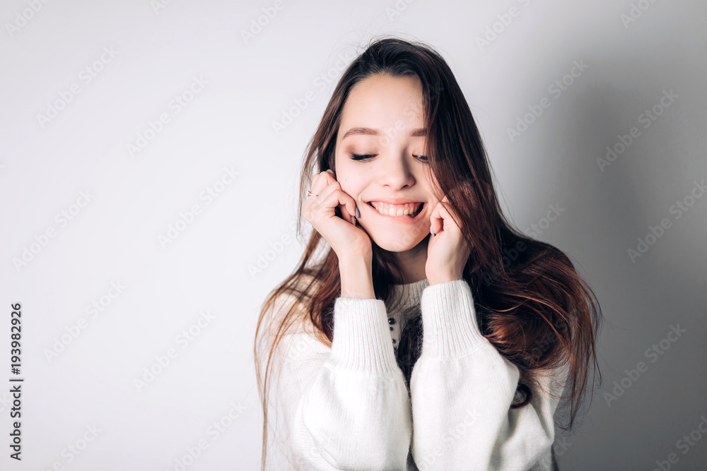 Smiling happy woman bites lip with a smile and looks down on white background. Emotions Smiling happy woman bites lip with a smile and looks down on white background. Emotions