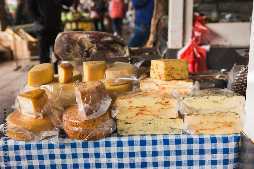 The farm food market. A lot of cheeses on the sales counter.