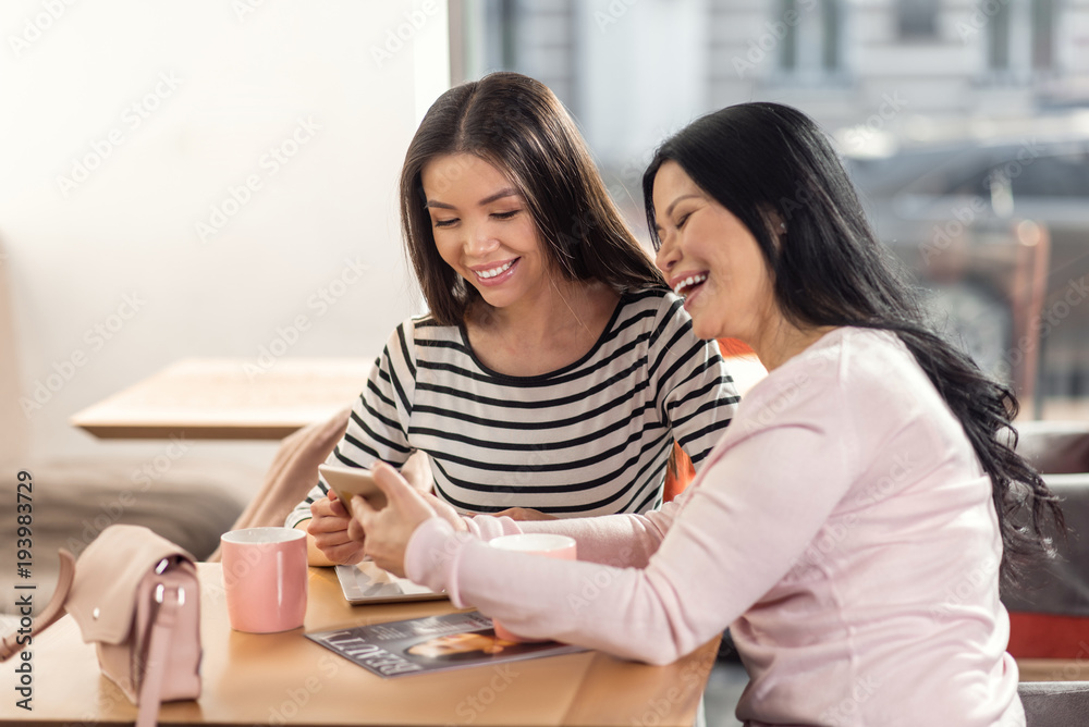 Great mood. Happy joyful nice women sitting together and looking at the photos while having fun Great mood. Happy joyful nice women sitting together and looking at the photos while having fun