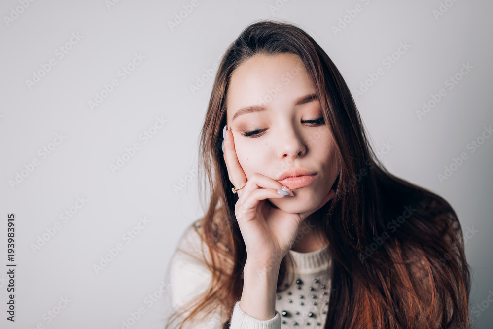 Close up of a sad and depressed woman looking to the side. Girl lowered her head and thinking about something on a white background.