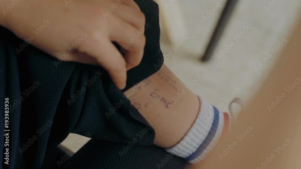 Smart and cheating student pulls up pants to check on cheat sheet formulas written down on leg skin during exam or test period in high school or university. Smart and cheating student pulls up pants to check on cheat sheet formulas written down on leg skin during exam or test period in high school or university.