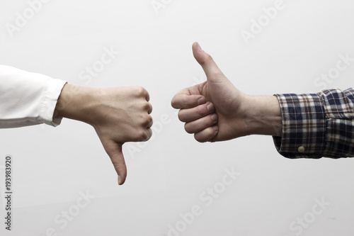 Two hands signalling thumbs up and thumbs down. The smooth hand on the left is making a thumbs up gesture while the hairy hand on the right is making a thumbs down gesture. photo