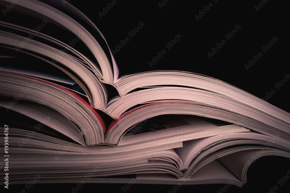 Macro view of book pages on black background. Space for text. Shallow DOF. Reading - Open Textbooks. Education concept. Close up opened book page Macro view of book pages on black background. Space for text. Shallow DOF. Reading - Open Textbooks. Education concept. Close up opened book page
