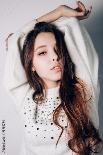 Close up portrait of a beautiful young woman in white sweater.