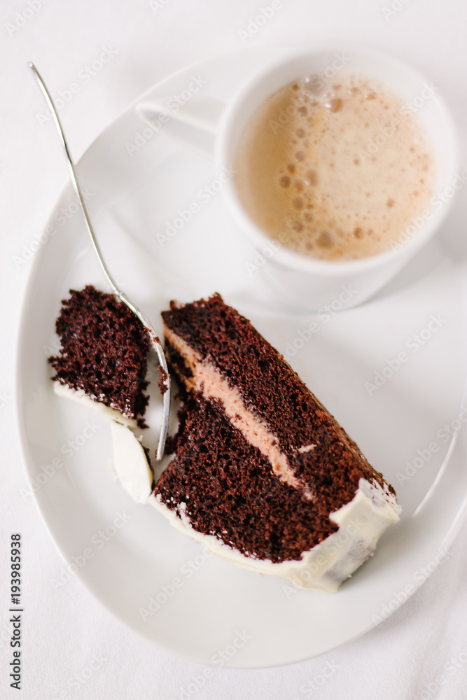 Cup of coffee with one piece chocolate cake and dessert fork on white background Cup of coffee with one piece chocolate cake and dessert fork on white background
