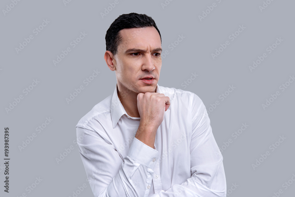 My thoughts. Good-looking thoughtful dark-eyed young man wearing a white shirt and holding his chin while thinking My thoughts. Good-looking thoughtful dark-eyed young man wearing a white shirt and holding his chin while thinking