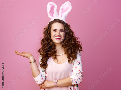 happy woman isolated on pink presenting something on empty palm