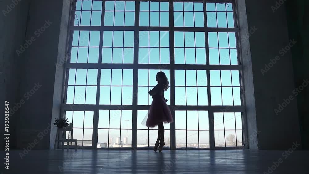 silhouette of a ballerina on a background of a large window. ballet dancer spinning in pointe shoes