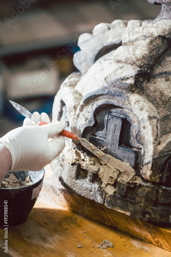 Conservator or restorer working on historical building piece photo