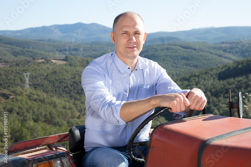 Male owner of vineyard driving tractor