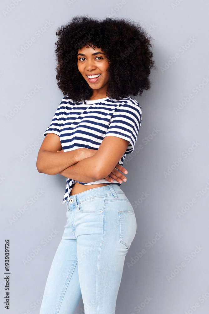 happy young african american woman smiling against gray background with arms crossed happy young african american woman smiling against gray background with arms crossed
