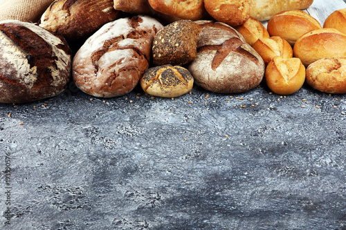 Different kinds of bread and bread rolls on board from above. Kitchen or bakery poster design