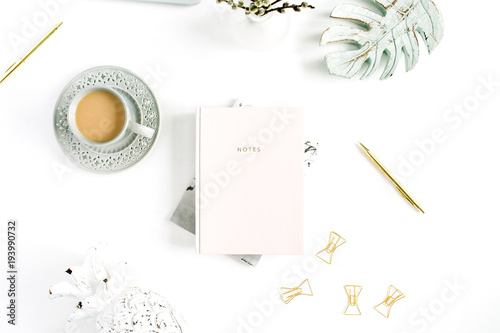 Flatlay of home office desk table. Workspace with pale pastel pink notebook and decorations on white background. Flat lay, top view.