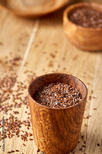 An overturned wooden bowl with linseeds on a rustic background, close-up, shallow depth of field, selective focus
