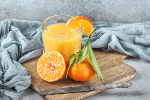 Fresh orange tangerines with green leaves and juice glass