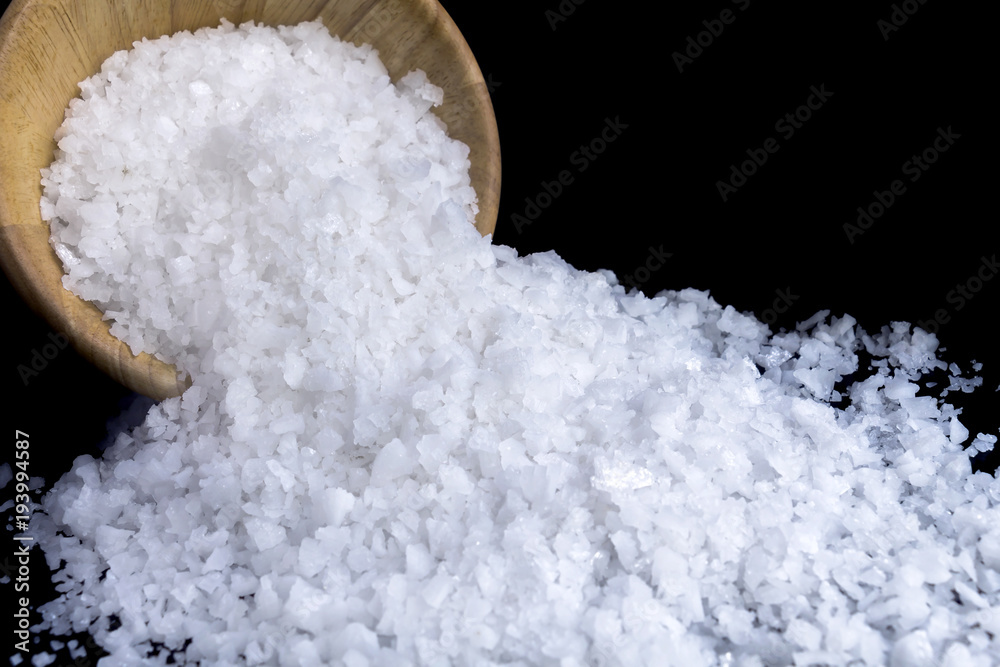 Sea salt white crystals in wooden bowl isolated on the gray background. Sea salt white crystals in wooden bowl isolated on the gray background.