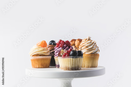 Платно close up view of various sweet cupcakes on cake stand isolated on white