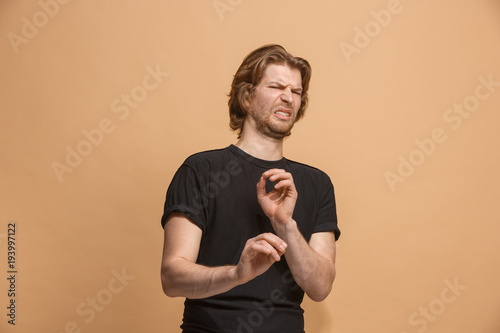 Young man with disgusted expression repulsing something, isolated on the pastel