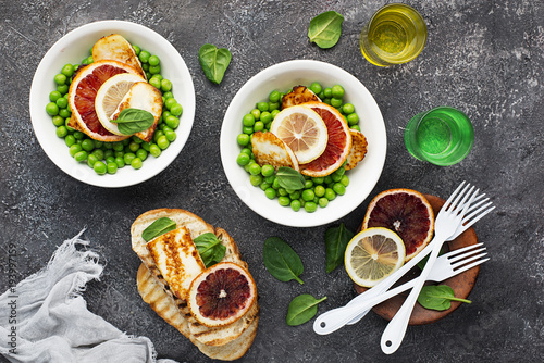 Green young peas  cheese haloumi  lemon. orange salad with slices of bread. Top View