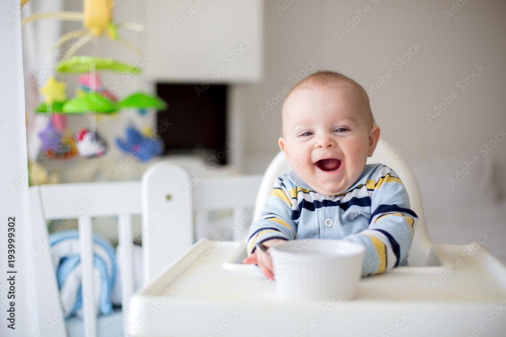 Cute little baby boy, eating mashed vegetables for lunch, mom feeding him Cute little baby boy, eating mashed vegetables for lunch, mom feeding him