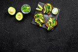 Snacks with avocado. Avocado toast with rye bread on black background top view copy space