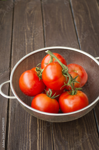 ripe tomatoes in a bowl on a dark wooden background
