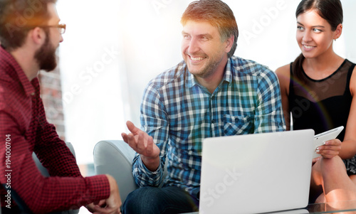 Portrait of smiling executives sitting with laptop in office