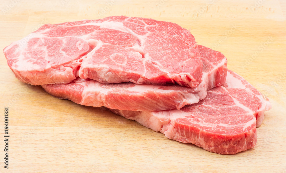 Raw pork neck meat cuts top view isolated on wood background fresh three slices without bone . Raw pork neck meat cuts top view isolated on wood background fresh three slices without bone .
