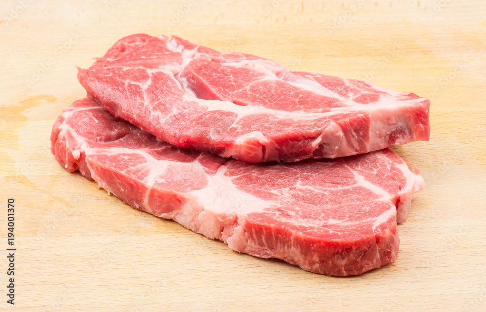 Two raw pork neck meat cuts isolated on wood background fresh slices without bone . Two raw pork neck meat cuts isolated on wood background fresh slices without bone .