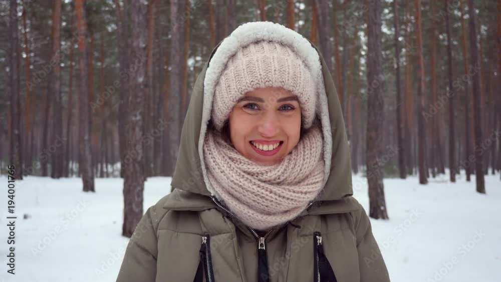 Smiling girl folded arms while standing in the wintry forest on a snowy day Smiling girl folded arms while standing in the wintry forest on a snowy day