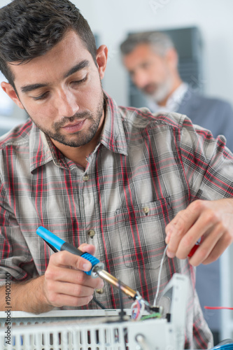 young repairman soldering electronics chips on radiator