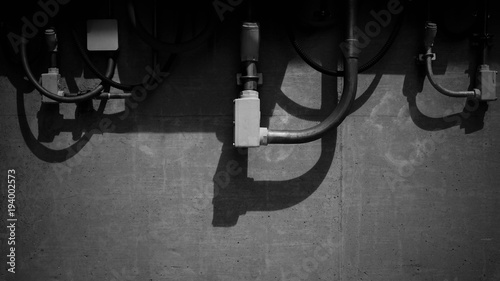 Pipe of electricity line on cement wall - monochrome