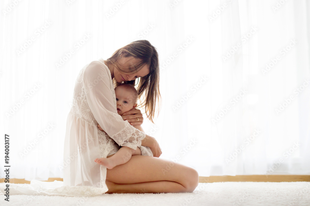 Young mother breastfeeding her newborn baby boy at home Young mother breastfeeding her newborn baby boy at home