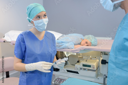 Patient face down on bed, nurse holding syringe photo