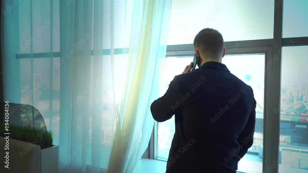 businessman talking on the phone in the office in front of the window businessman talking on the phone in the office in front of the window