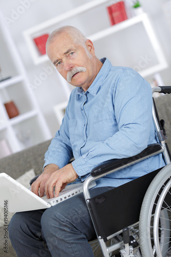 mature man in a wheelchair working on a laptop